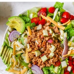 Cheeseburger salad with avocado, red onion, cheddar cheese, tomatoes, ground turkey and pickles.