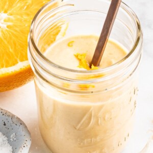 Citrus tahini dressing in a jar, topped with orange zest.