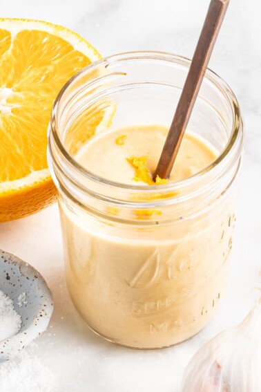 Citrus tahini dressing in a jar, topped with orange zest.