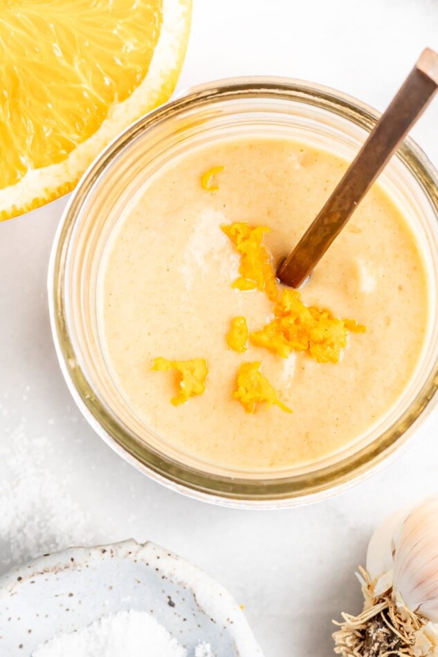 Citrus tahini dressing in a jar, topped with orange zest.