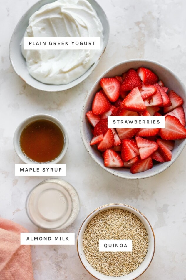 Yogurt, strawberries, maple syrup, almond milk and quinoa measured out into bowls.
