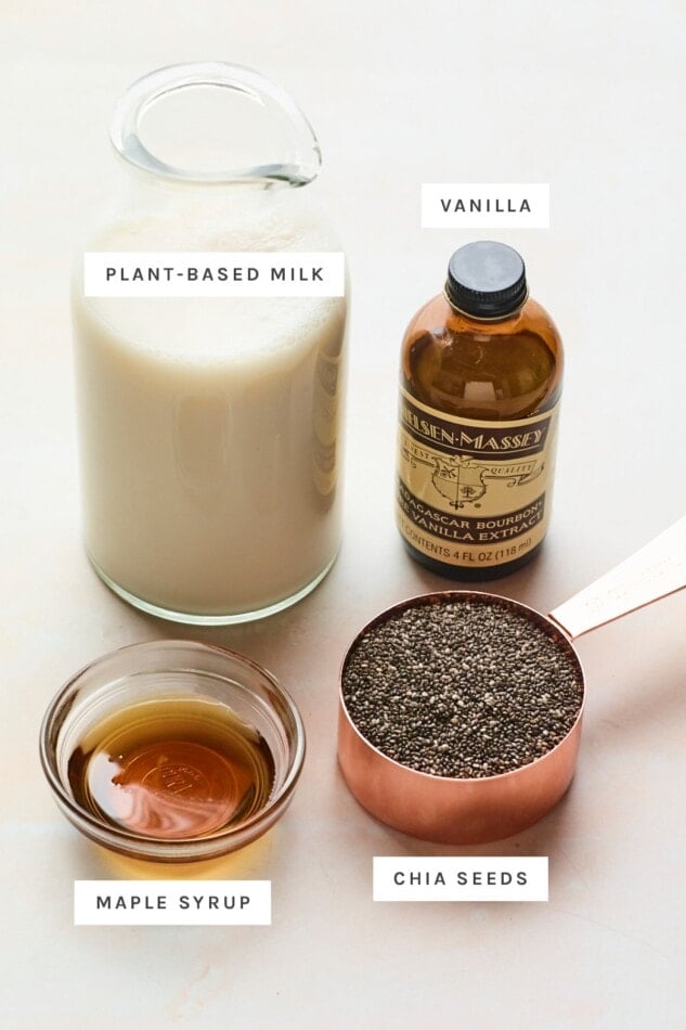 Bottle of plant milk, jar of vanilla, bowl of maple syrup and a measuring cup of chia seeds.
