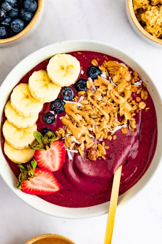 Acai bowl topped with banana, blueberries, strawberries, granola and peanut butter.