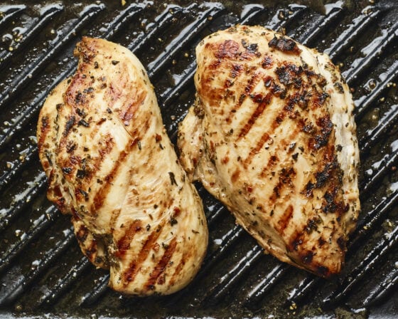 Two chicken breasts grilling on a grill pan.
