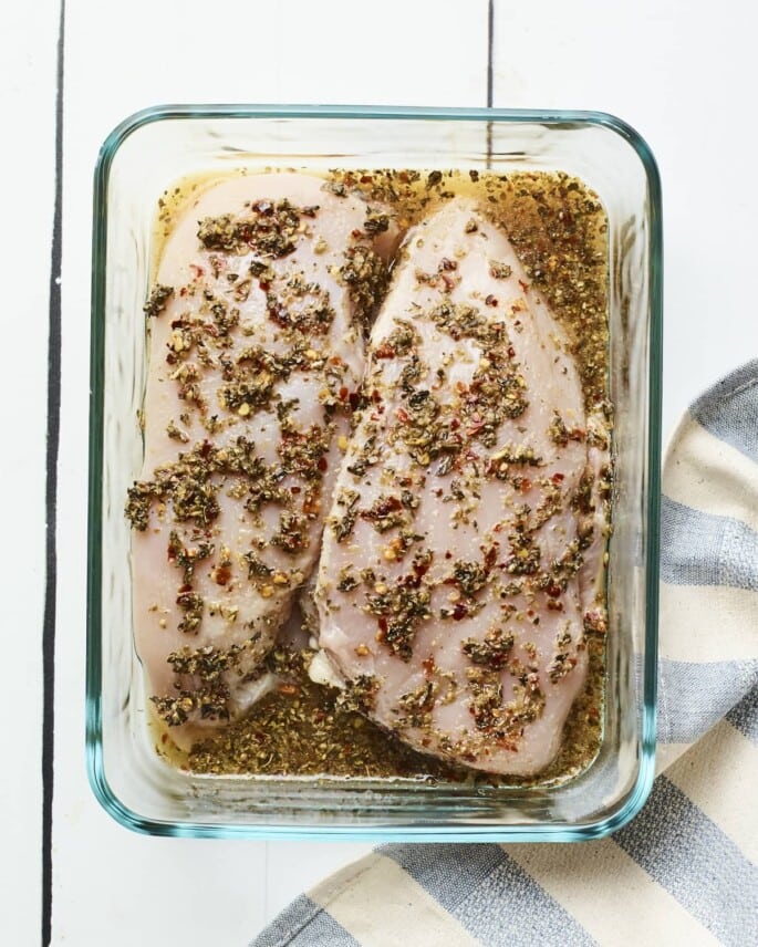 Two chicken breast being marinated in apple cider vinegar mixture.