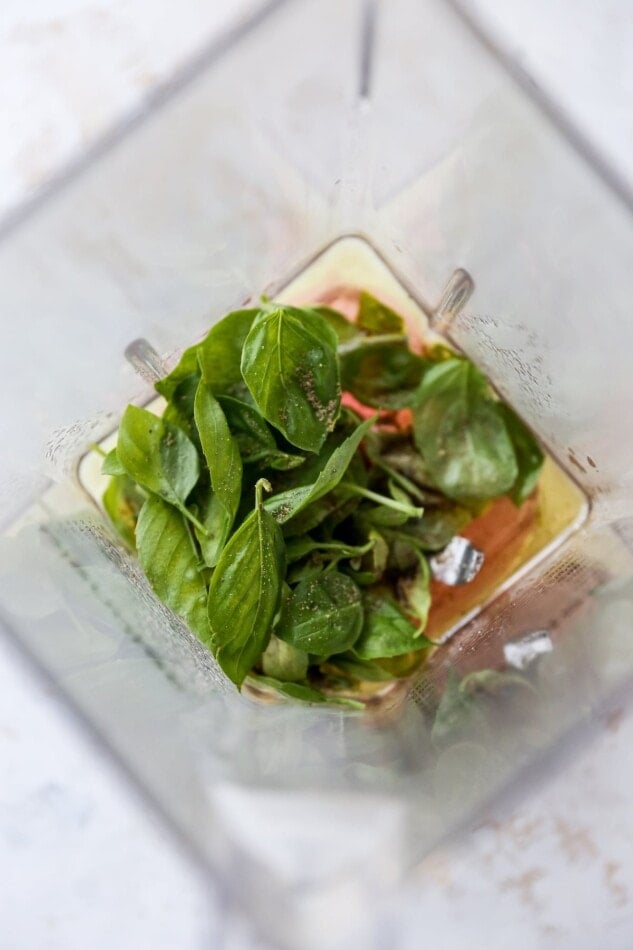 Blender with basil, oil and vinegar before being blended.