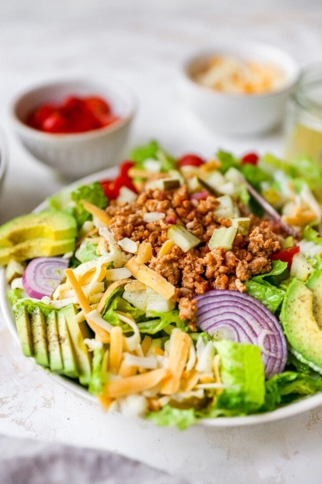 Cheeseburger salad with avocado, red onion, cheddar cheese, tomatoes, ground turkey and pickles.