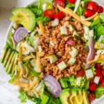 Cheeseburger salad with avocado, red onion, cheddar cheese, tomatoes, ground turkey and pickles.