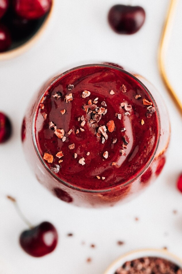 Chocolate cherry smoothie in a glass and topped with cacao nibs.