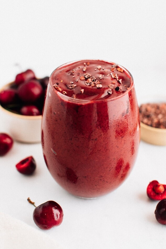 Chocolate cherry smoothie in a glass and topped with cacao nibs.