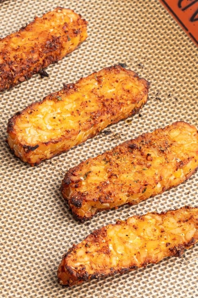 Slices of baked blackened tempeh on a sheet pan.