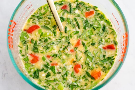 Egg white mixture in a pyrex jar with spinach and red pepper.