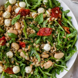 Farro salad with arugula, beans, tomatoes and mozzarella in a serving bowl.