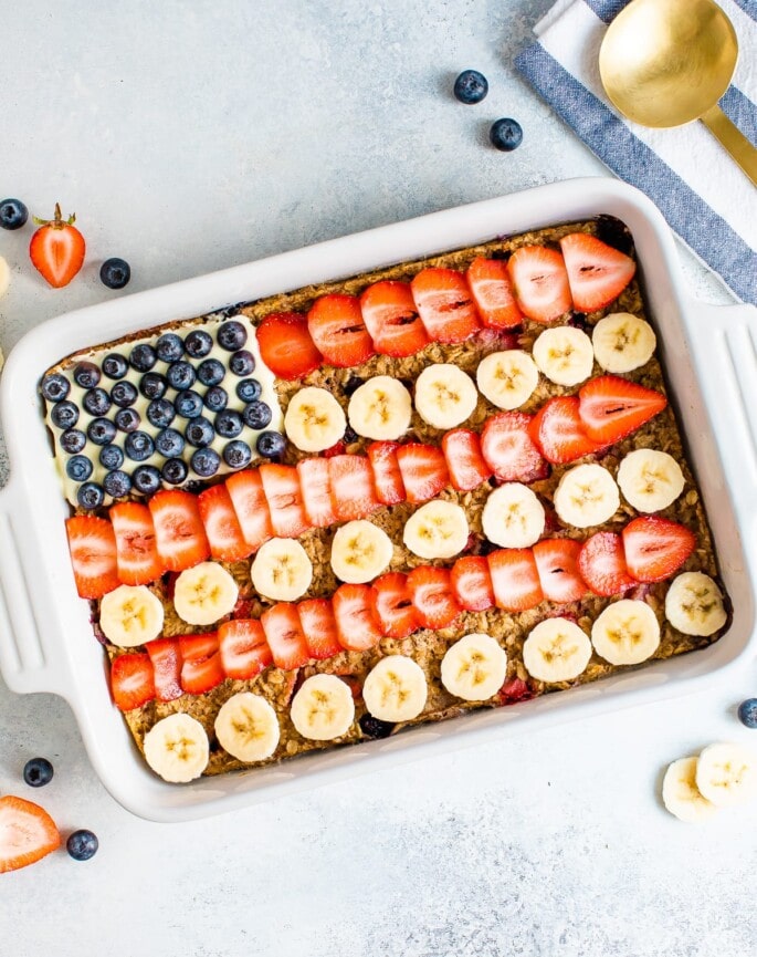 Baked oatmeal decorated to look like the American flag with blueberries, banana slices and strawberries.