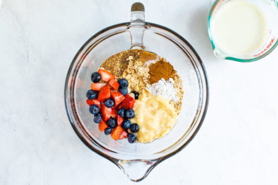 Mixing bowl with oats, baking powder, flax, berries and banana.