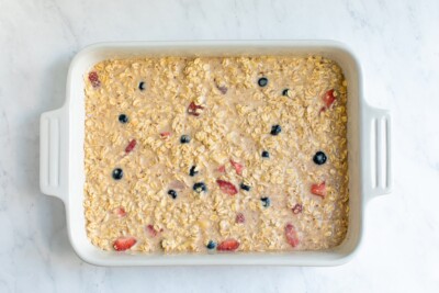 Baked oatmeal mixture with berries in a baking dish before being baked.