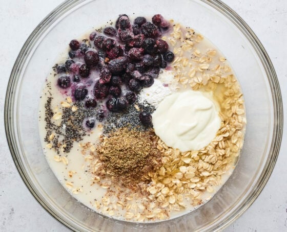 Mixing bowl with oats, milk, blueberries, yogurt, baking powder, flaxseed, lemon juice and poppyseeds.