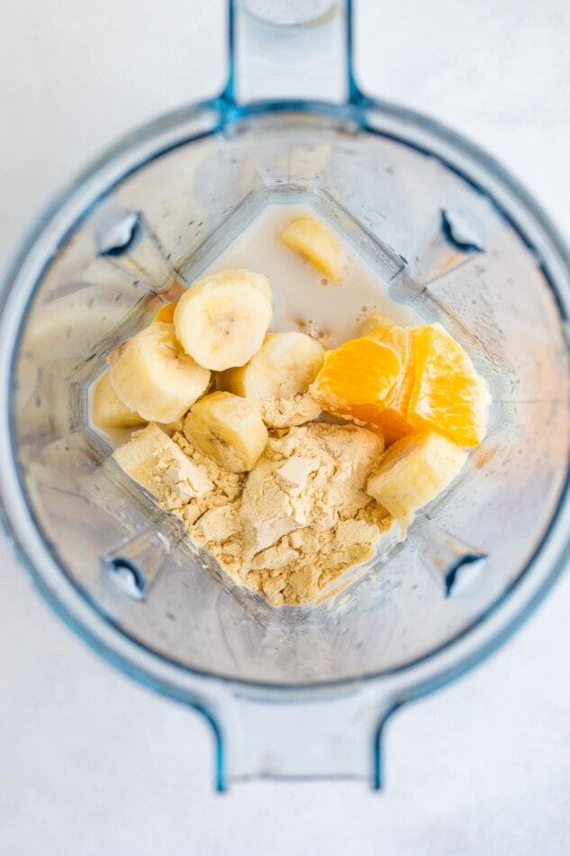 Milk, banana, protein powder and orange in a blender.