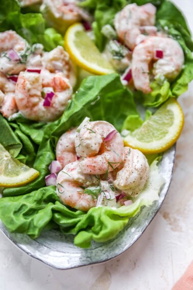 Shrimp salad served on lettuce cups. Lettuce cups are on a serving platter.