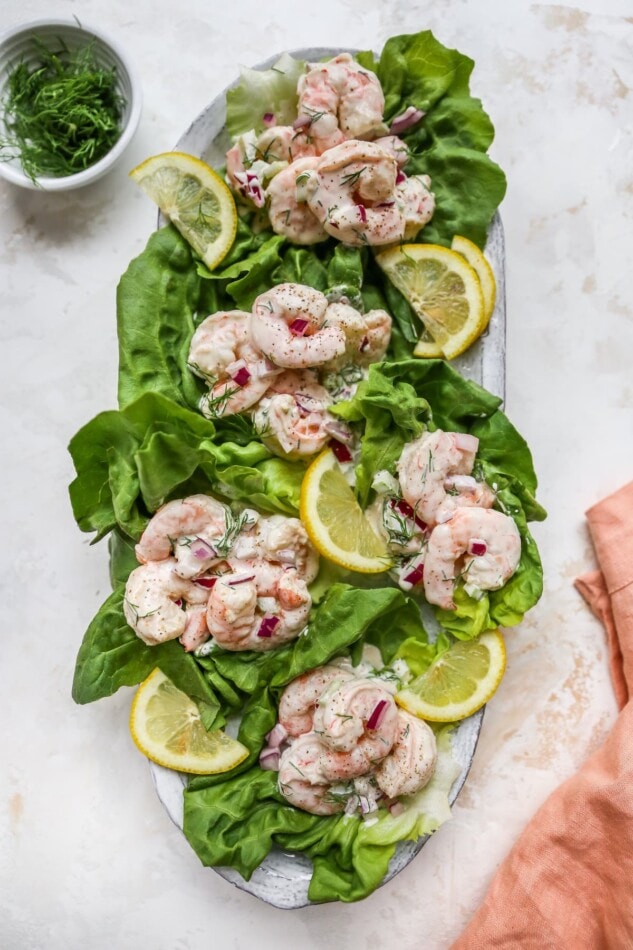Shrimp salad served on lettuce cups. Lettuce cups are on a serving platter.
