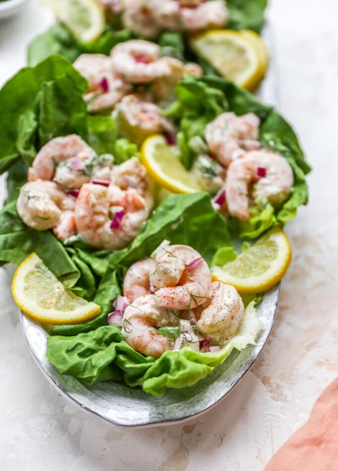 Shrimp salad served on lettuce cups. Lettuce cups are on a serving platter.
