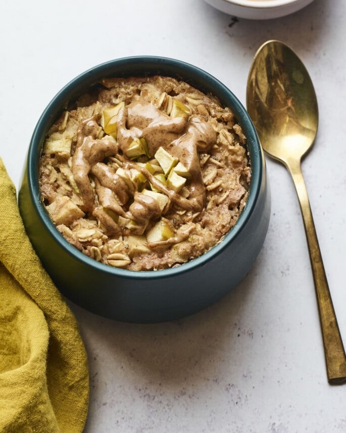 Bowl of apple cinnamon baked oatmeal. A spoon and napkin are next to the bowl.