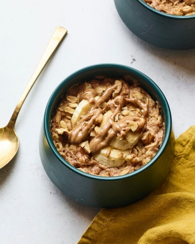 Bowl of banana walnut baked oatmeal. A spoon and napkin are next to the bowl.