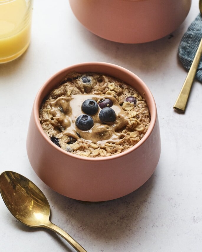 Bowl of blueberry baked oatmeal. Spoon is next to the bowl.