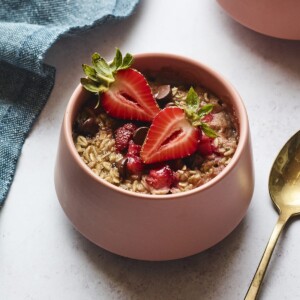 Bowl of strawberry chocolate chip baked oatmeal. A spoon and napkin are next to the bowl.