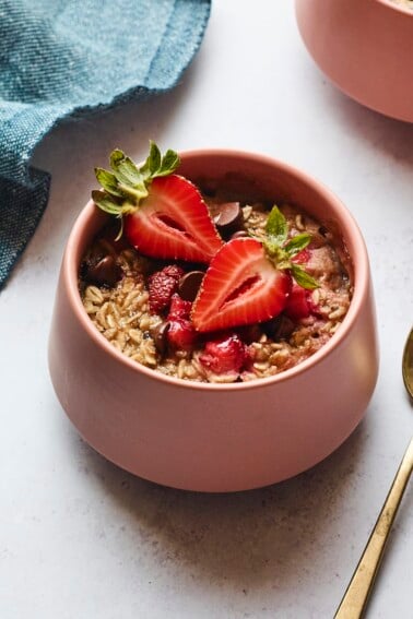 Bowl of strawberry chocolate chip baked oatmeal. A spoon and napkin are next to the bowl.