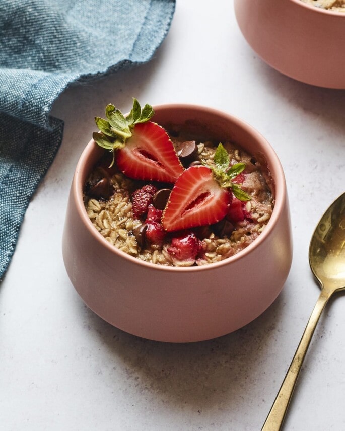 Bowl of strawberry chocolate chip baked oatmeal. A spoon and napkin are next to the bowl.