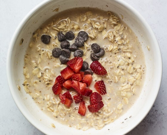 Mixing bowl with baked oatmeal mixture and chocolate chips and strawberries.