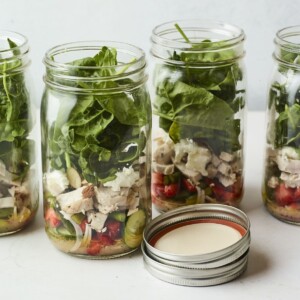 Four mason jars filled with a strawberry spinach chicken salad.