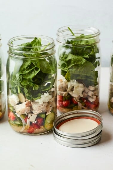 Four mason jars filled with a strawberry spinach chicken salad.