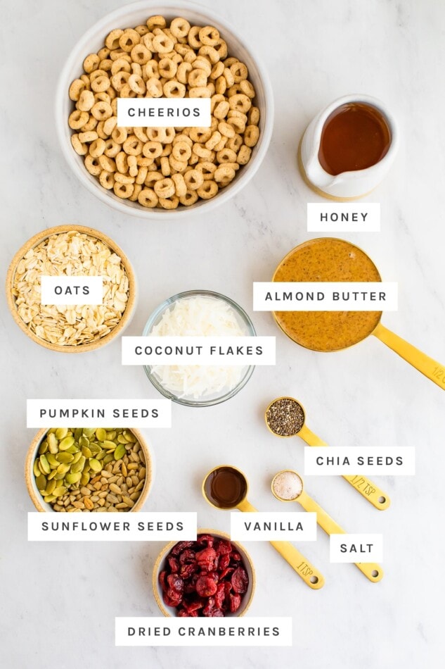 Ingredients for cereal bars laid out on a marble surface with labels. 