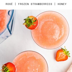 Two glasses of frose garnished with strawberries.