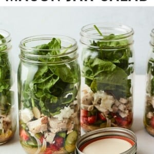Mason jars filled with a strawberry spinach salad with chicken.