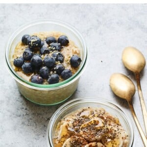 Two glass bowls of overnight steel cut oats. One it topped with blueberries and the other is topped with banana, maple and chia seeds.