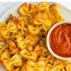 Pasta chips on a plate with a small bowl of marinara for dipping.