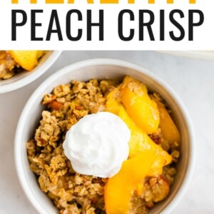 Peach crisp in a bowl topped with whipped cream.