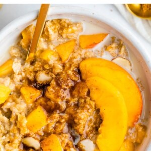 Peaches and cream oatmeal in a white bowl with fresh peaches and oat milk on top.