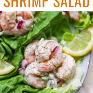 Shrimp salad served on a bed of lettuce and garnished with a slice of lemon.