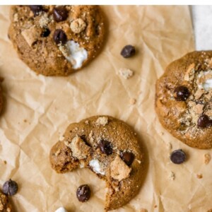 S'mores cookies on parchment paper. One has a bite taken out of it.