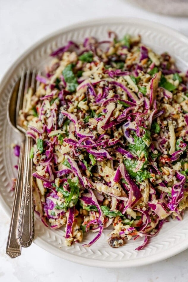 Serving plate with apple slaw. A serving fork and spoon are on the bowl.