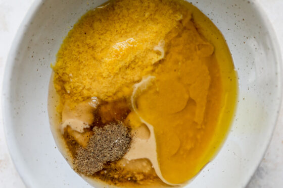 Tahini, nutritional yeast, vinegar, oil and spices in a bowl.