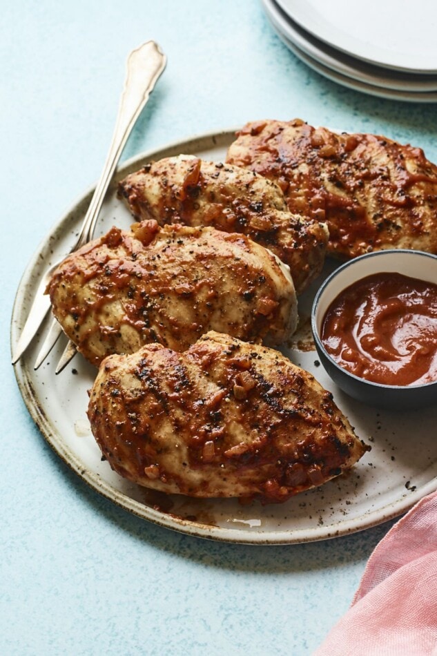 Plate with 4 bbq chicken breasts and a bowl of homemade bbq sauce.