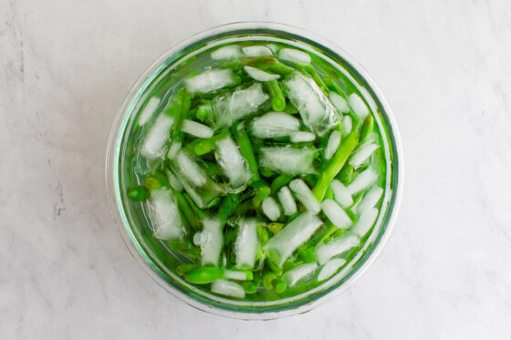 Blanched green beans in a ice water bath.