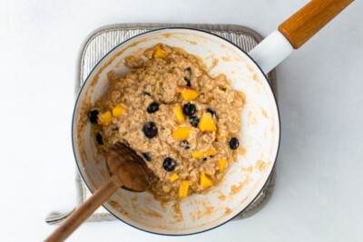 White saucepan with cooked blueberry peach oatmeal.