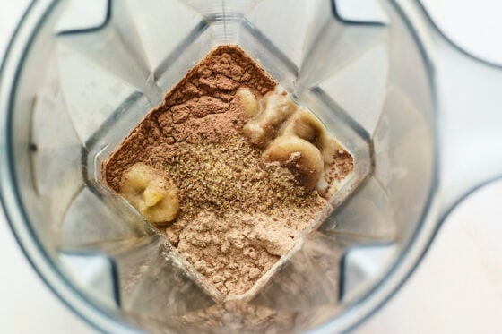 Frozen banana, milk and chocolate protein powder in a blender.