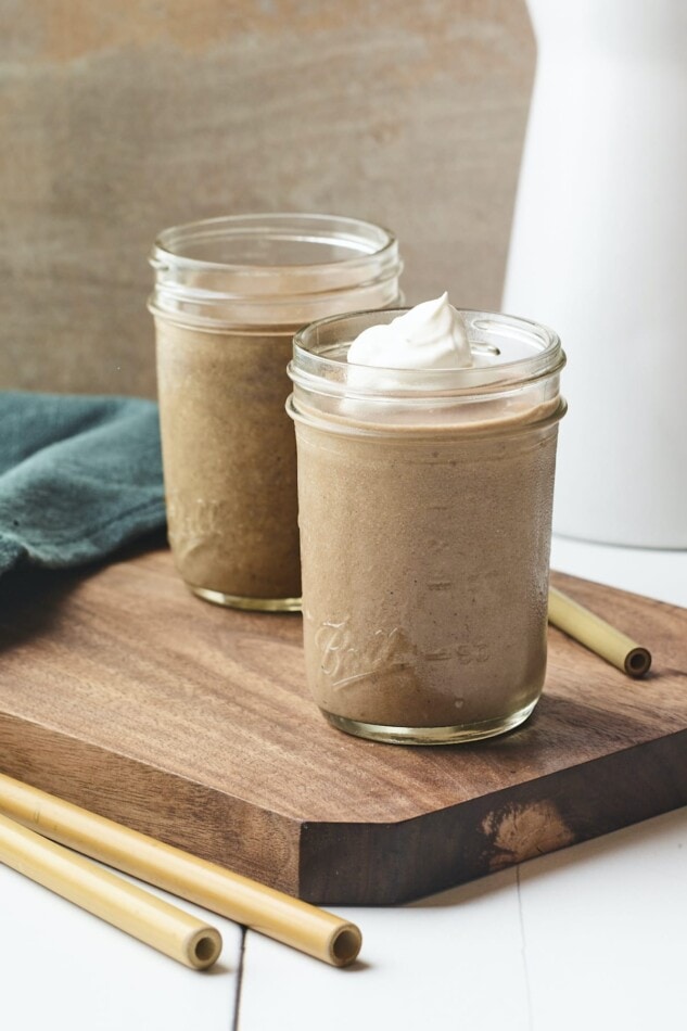 Chocolate protein shake in in two mason jars topped with whipped cream.